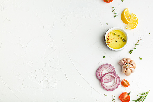 Food cooking background on white stone rustic table with fresh ingredients, vegetables, herbs, spices, olive oil from above with space for text