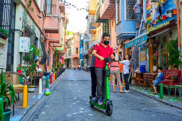Ordinary life in the old district of Istanbul. two guys are riding along a narrow street on one electric scooter Ordinary life in the old district of Istanbul. two guys are riding along a narrow street on one electric scooter. Turkey , Istanbul - 07.20.2020 lime scooter stock pictures, royalty-free photos & images