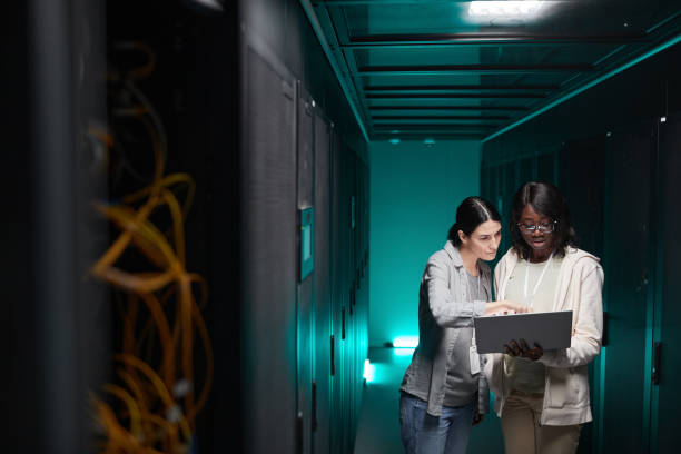 dos mujeres administrando la red de servidores - data center computer programmer women fotografías e imágenes de stock