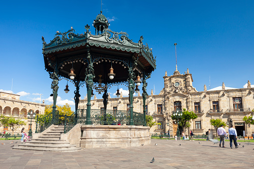 Guadalajara, Jalisco, Mexico - January 20, 2020: People walking in the plaza by the gazebo and Governor's Palace in Guadalajara, Mexico on a sunny day.
