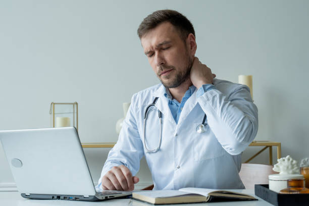 Man doctor is stressed and tired from hard work to take care of patients. Male doctor tired after shift stock photo