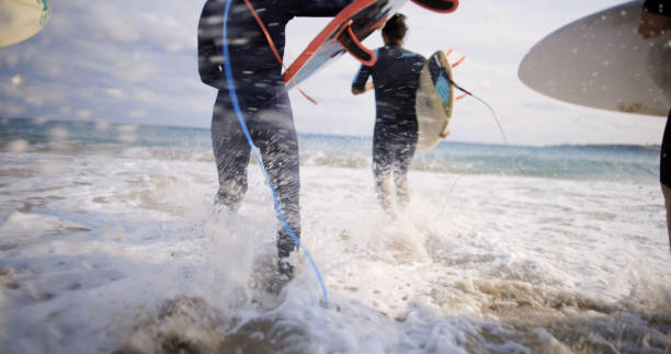 Japan surfing , sometimes during a typhoon, there are many waves in Japan especially in Hebara, Katsuura, Chiba. Westerner surfs large waves. Sunrise & at the beach with a surfer & his surf board.
