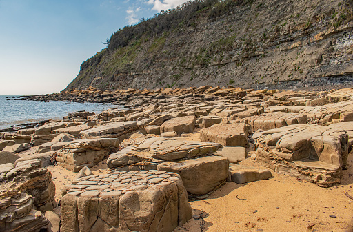 A view across the fossil shapes on the orange rock strewn shore at the Jurasic cliffs of Kimmeridge Bay, Dorset