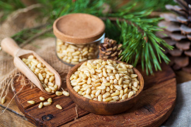 istock Pine nuts in a bowl, pine cone, branch, glass jar on a cutting board. Still life from natural ingredients, side view. 1314588355