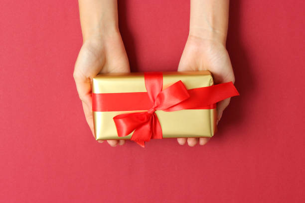 istock gift in female hands on a colored background top view. 1314591240