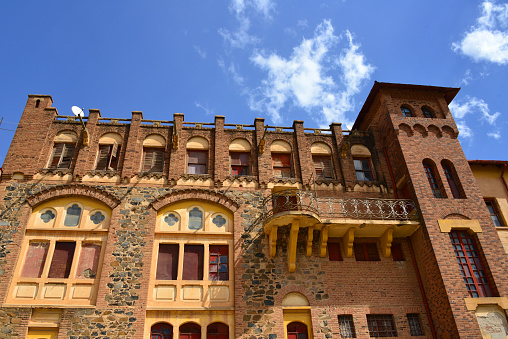 Asmara, Eritrea: Asmara Opera Theater, Romanesque and Renaissance style, designed by the Engineer Odoardo Cavagnari in 1919 for the ARPA Company (Anonima Ritrovi Pubblici Asmara) and the Dilsizian Frères Company of Milan - fortress-style architecture - the red brick western facade, designed with battlements, a tower and a balcony mounted on corbels - Harnet Avenue / Viale Mussolini and Beleza Street / Via della Croce del Sud - Teatro di Asmara - Asmera, a Modernist City of Africa - UNESCO World Heritage Site.