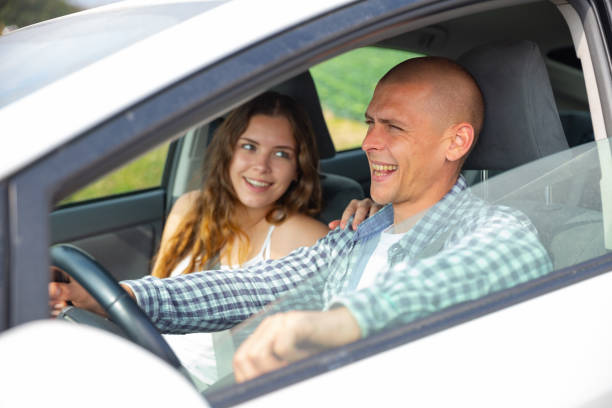 istock Cheerful man driving car with girlfriend in passenger seat 1314592182
