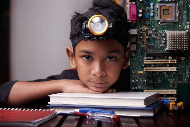 Little boy holding the motherboard, studying computer component at home stock photo