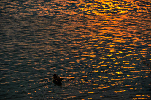 Two (not recognizeable) fishermen in a dug-out canoe at the last daylight. Lake Albert, Uganda.