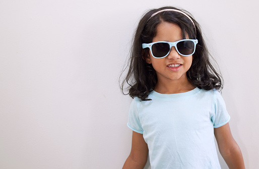 fashionable baby girl sitting in sunglasses in the grass on nature