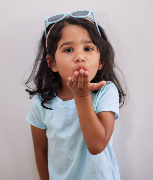 Shot of an adorable little girl blowing a kiss while standing against a wall I'm blowing some kisses your way blowing a kiss stock pictures, royalty-free photos & images