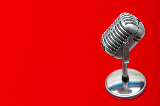 The retro vintage microphone on red background