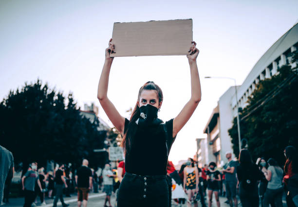 donna che protesta in strada con cartello bianco - need a change foto e immagini stock