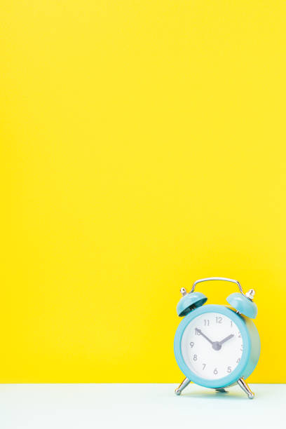 istock blue alarm clock over yellow background. studio shot. time concept. template for design 1314606170