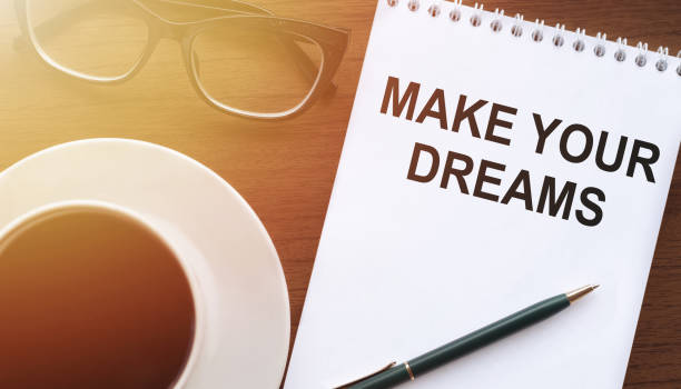 istock Make your dreams, the text is written on a notebook with glasses and coffee on the table. Sunlight is falling. Concept of desire to keep the chosen goals and dreams. 1314608121