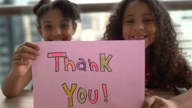 Sisters holding a paper with 'thank you' written