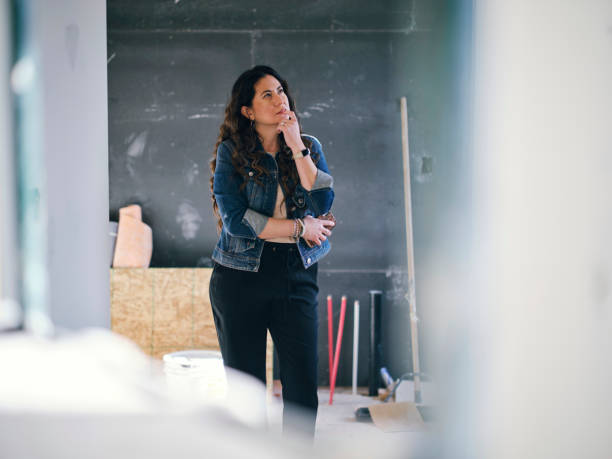 femme regardant une maison en construction - decisions women thinking latin american and hispanic ethnicity photos et images de collection