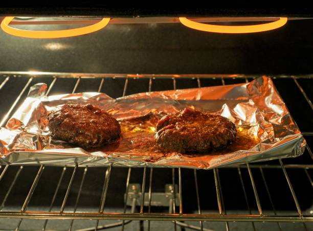 greasy hamburgers being broiled in an electric stove - broiling imagens e fotografias de stock