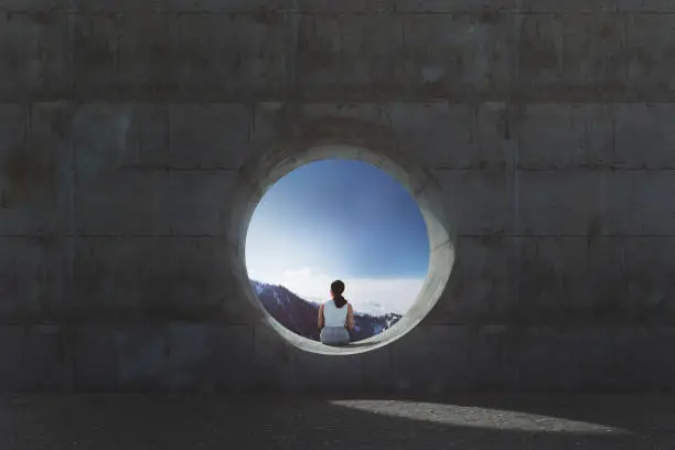 Photo of Lonely young woman sitting and looking through concrete window
