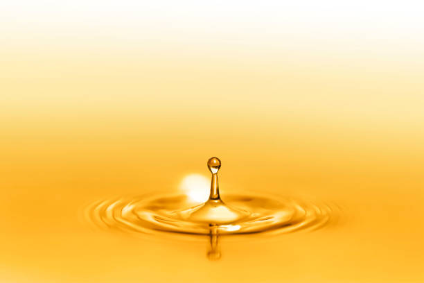 黄金の反射で輝く健康的なエキストラバージンオイルのドロップスプラッシュにクローズアップ。 - 液体 ストックフォトと画像