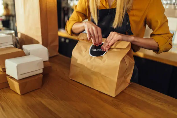 Photo of Close up of woman packing food for delivery