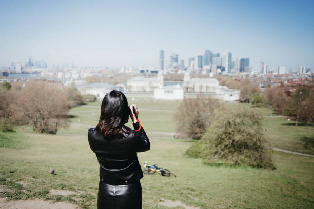 United Kingdom, London, Greenwich park - 05.25.2024\nPeople walking in Greenwich park, in a Spring day, with skyscrapers panorama behind