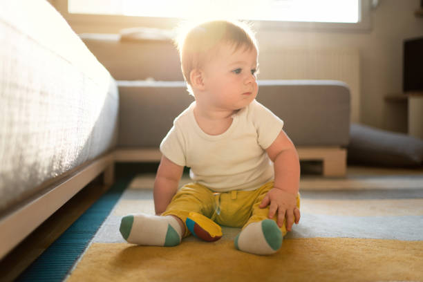 istock Baby boy sitting on the floor and looking away 1314635628