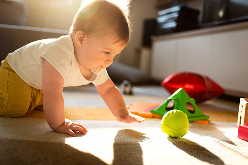 Caucasian baby boy with toys on the floor of his playroom.