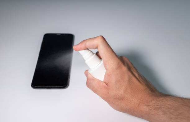 istock Man using disinfectant on mobile. The man cleans the mobile phone of possible bacteria. Man cleaning the smartphone with disinfectant. 1314637239