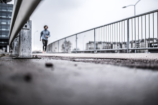 Young athletic man running outdoors on cold and rainy day in the city. Focus on foreground. Concept photo. Running motivation.