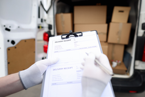 Courier holds receipt for delivery of goods. Receiving parcels and reporting concept
