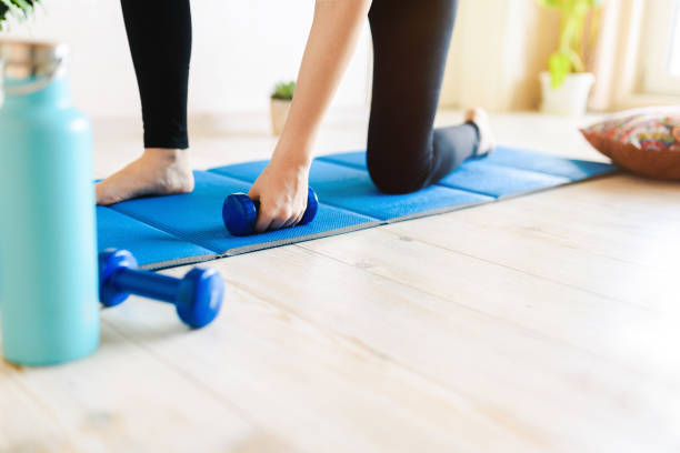 istock Young woman training on a mat with dumbbell weights. 1314643594