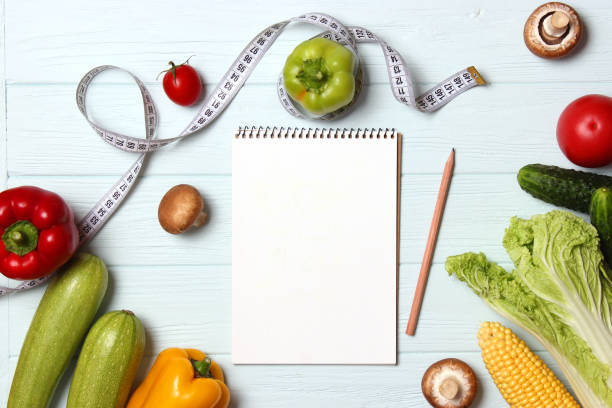 istock Fresh vegetables, measuring tape and paper notepad on wooden table. 1314653589