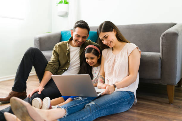 Parents and kid doing online shopping Hispanic family calling by video call their friends. Happy mom, dad and daughter talking with their loving family during an online video chat in a laptop young family stock pictures, royalty-free photos & images