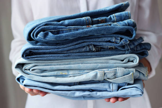 pila de jeans doblados en las manos - denim fotografías e imágenes de stock