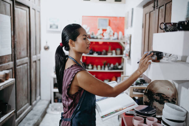 istock Craftswoman making ceramic pot in studio. Pottery maker inspecting newly made ceramic pot in workshop 1314679522