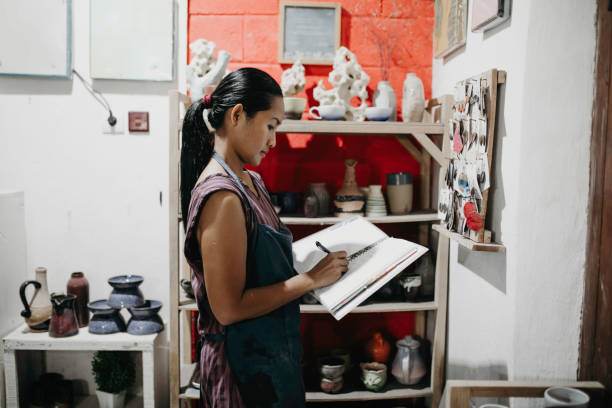 istock Craftswoman making ceramic pot in studio. Pottery maker inspecting newly made ceramic pot in workshop 1314679553