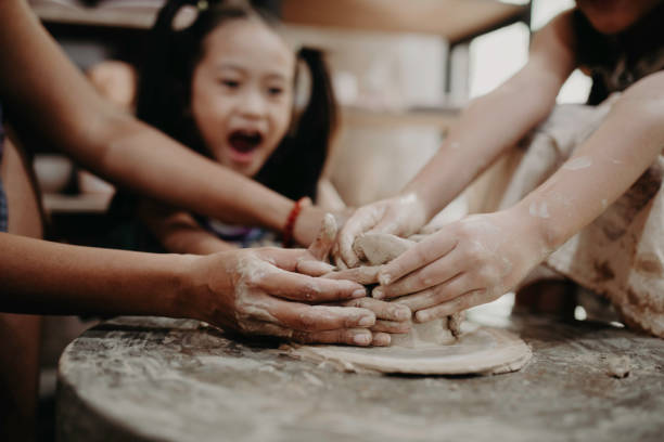 Young woman making ceramics in her workshop with her child, working parents and small business concept