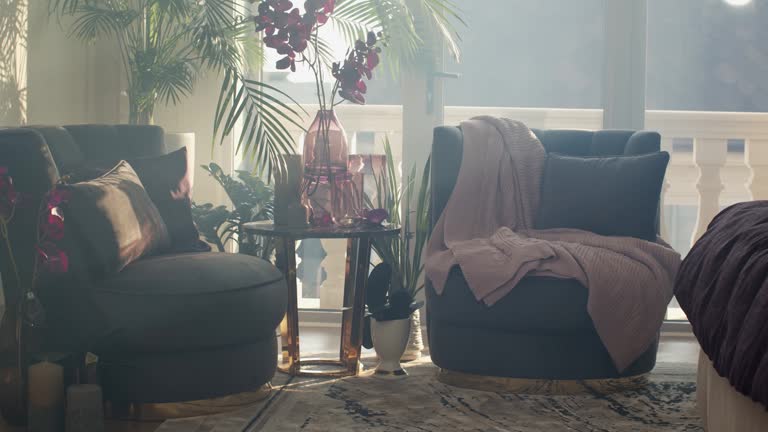 Corner of a bedroom with two dark violet armchairs and round coffee table.