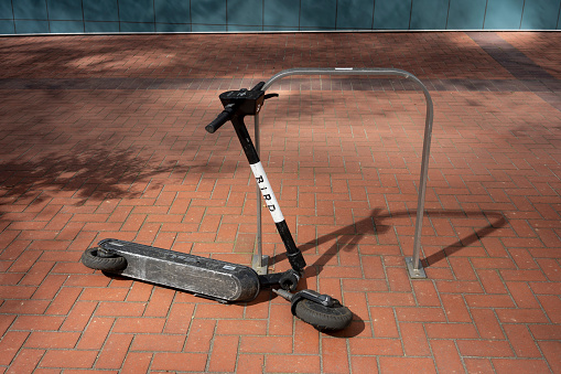 Portland, OR, USA - Apr 18, 2021: A broken BIRD branded electric scooter is seen on the street in Portland, Oregon. Electric scooters are vanishing from more cities amid the coronavirus pandemic.