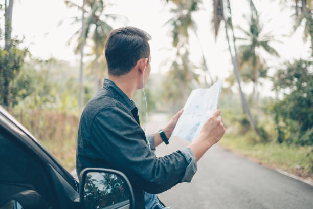 istock A man with backpack hiking read a map side car on the road in forest. Backpack travel concept. 1314689303