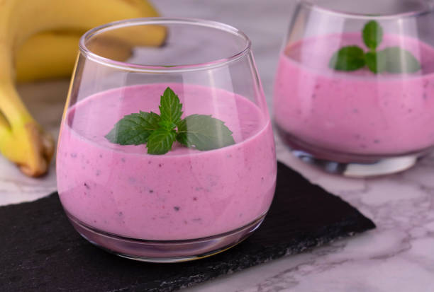 istock Berry banana smoothie garnished with mint on a marble background. Close-up. 1314691251