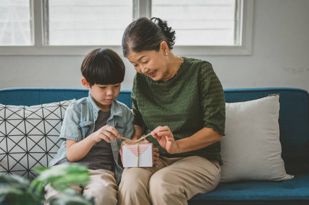 podekscytowana babcia i wnuk rozpakowujący prezent urodzinowy razem - grandmother giving gift child zdjęcia i obrazy z banku zdjęć