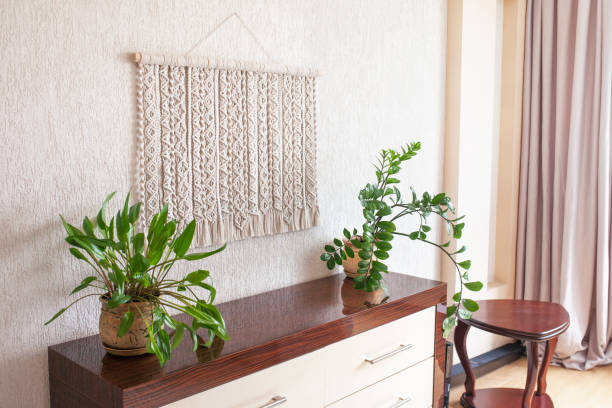 Handmade macrame. 100% cotton wall decoration with wooden stick hanging on a white wall. Macrame braiding and cotton threads. Female hobby. ECO friendly modern knitting DIY natural decoration concept in the interior macrame hecho a mano. decoración de pared 100% algodón con palo de madera colgado en una pared blanca. trenzado macrame y hilos de algodón. afición femenina. eco amigable moderno knitting diy concepto de decoración natural en el interior