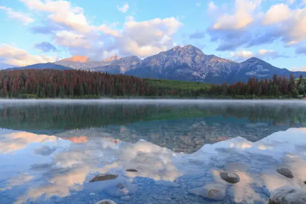 Sunrise of Pyramid Lake with Reflections of trees, mountains and clouds in water. Jasper National Park