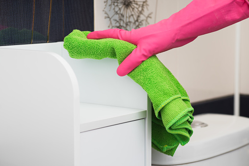 Closeup hand with pink  gloves holding green duster microfiber cloth for cleaning