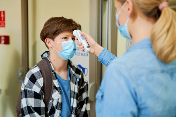 istock Teacher checking the temperature of the students before entering the school 1314710708