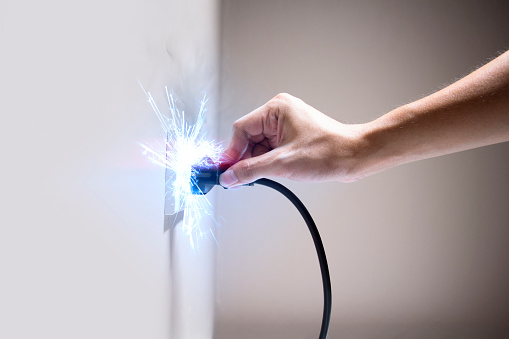 Hand connecting electrical plug cause electric shock, Idea for causes of home fire, Electric short circuit, Electrical hazard can ignite household items