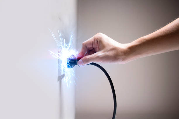 Hand connecting electrical plug cause electric shock, Idea for causes of home fire, Electric short circuit, Electrical hazard can ignite household items stock photo