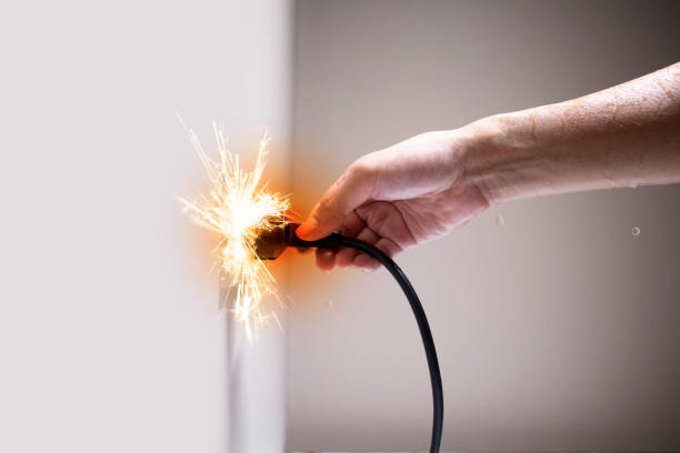 Wet hand connecting electrical plug cause electric shock, Idea for causes of home fire, Electric short circuit, Electrical hazard can ignite household items, Residential building electrical fires. stock photo